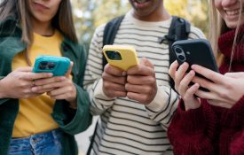 Close-up of three students looking at their phones.
