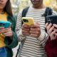 Close-up of three students looking at their phones.