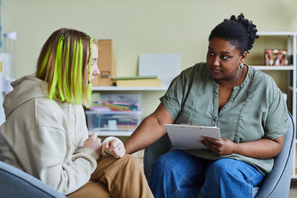 Psychologist working with upset girl at office.